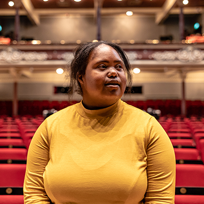 A black woman with a learning disability admires a grand theatre.